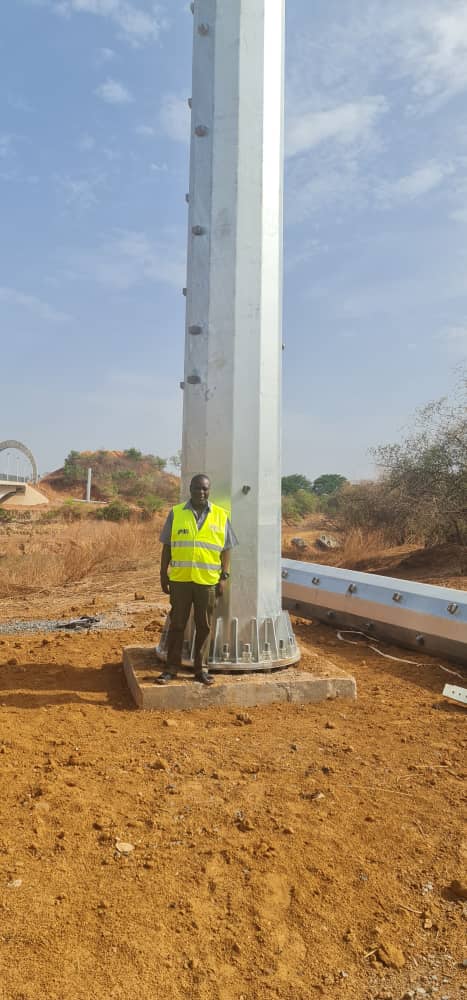 PIU official standing beside a large electricity transmission pole